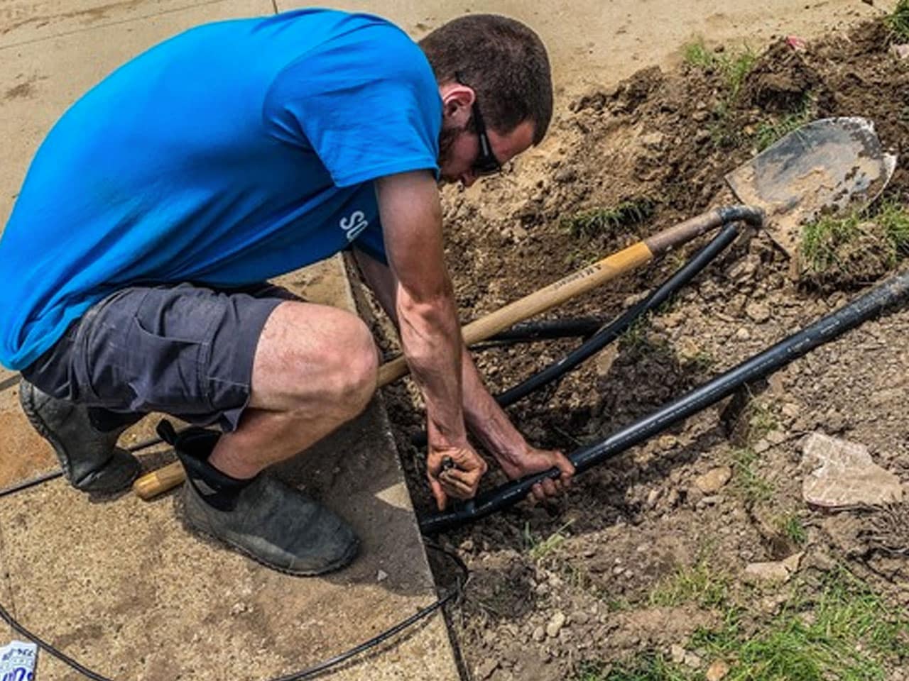 photo of a man working to replace an irrigation system.